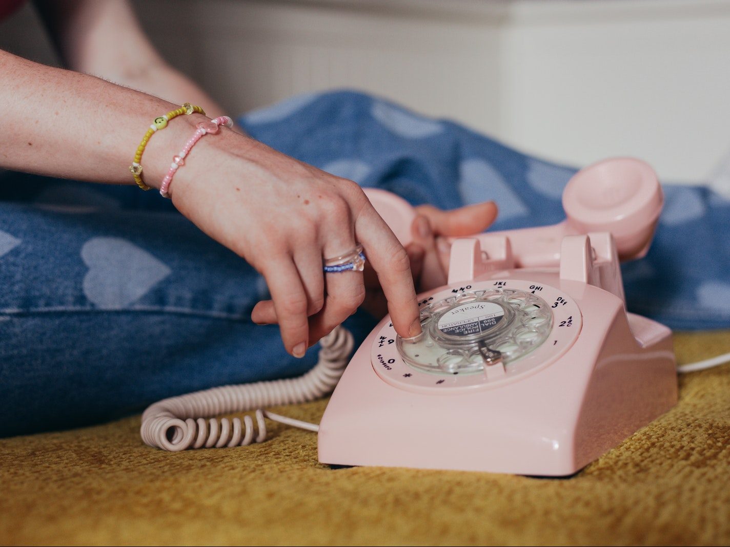 Close-Up Photo of a Person Using a Pink Rotary Phone