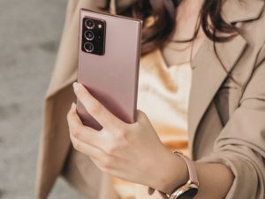 woman in beige blazer holding white smartphone