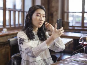 Woman in White and Black Long Sleeve Shirt Holding Black Smartphone