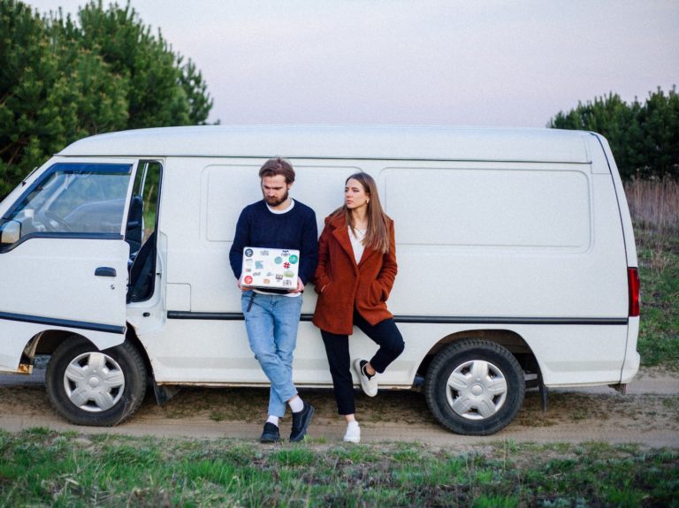 Woman and a man leaning on a White Van