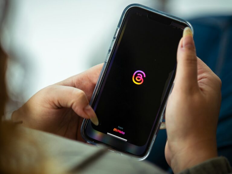 a woman holding a cell phone with a logo on it