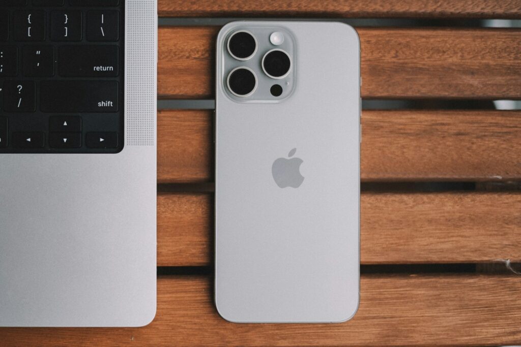 An iPhone and a laptop on a wooden table