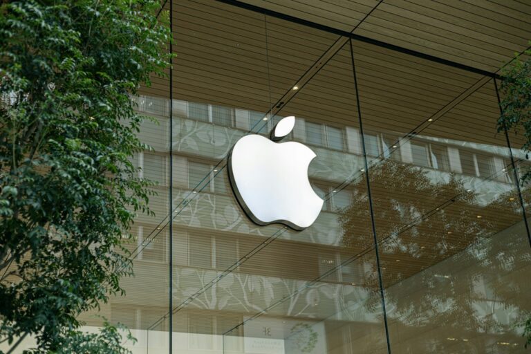 the apple logo is reflected in the glass of a building